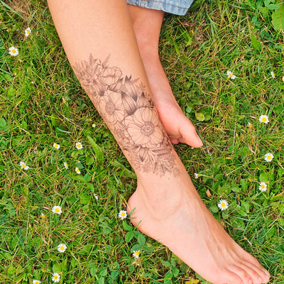 Tatouage temporaire hyperréaliste Black Anemones de ArtWear Tattoo Fleurs sur le bras d'un homme et jambe d'une femme