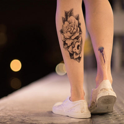 Tatouage temporaire hyperréaliste B&W Flowers de ArtWear Tattoo Fleurs sur le bras d'un homme et jambe d'une femme