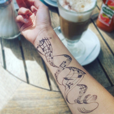 Tatouage temporaire hyperréaliste Music Notes de ArtWear Tattoo Géométriques sur le bras d'un homme et jambe d'une femme