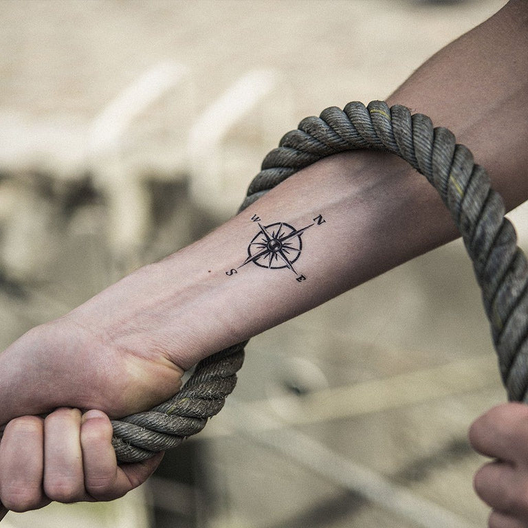 Tatouage temporaire hyperréaliste Small Compass de ArtWear Tattoo Minimalistes sur le bras d'un homme et jambe d'une femme