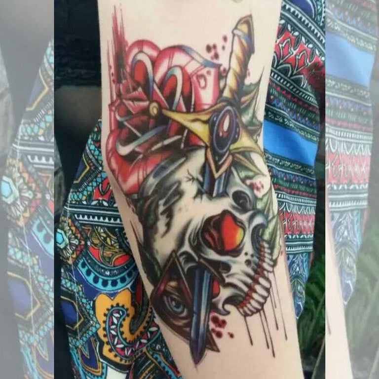 Tatouage temporaire hyperréaliste Skull Sword & Roses de ArtWear Tattoo Old School sur le bras d'un homme et jambe d'une femme