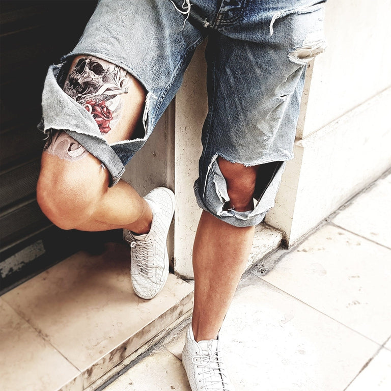 Tatouage temporaire hyperréaliste Skull Gun Rose - White Touch de ArtWear Tattoo Tête de mort sur le bras d'un homme et jambe d'une femme
